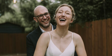 laughing bride and groom with trees in the background