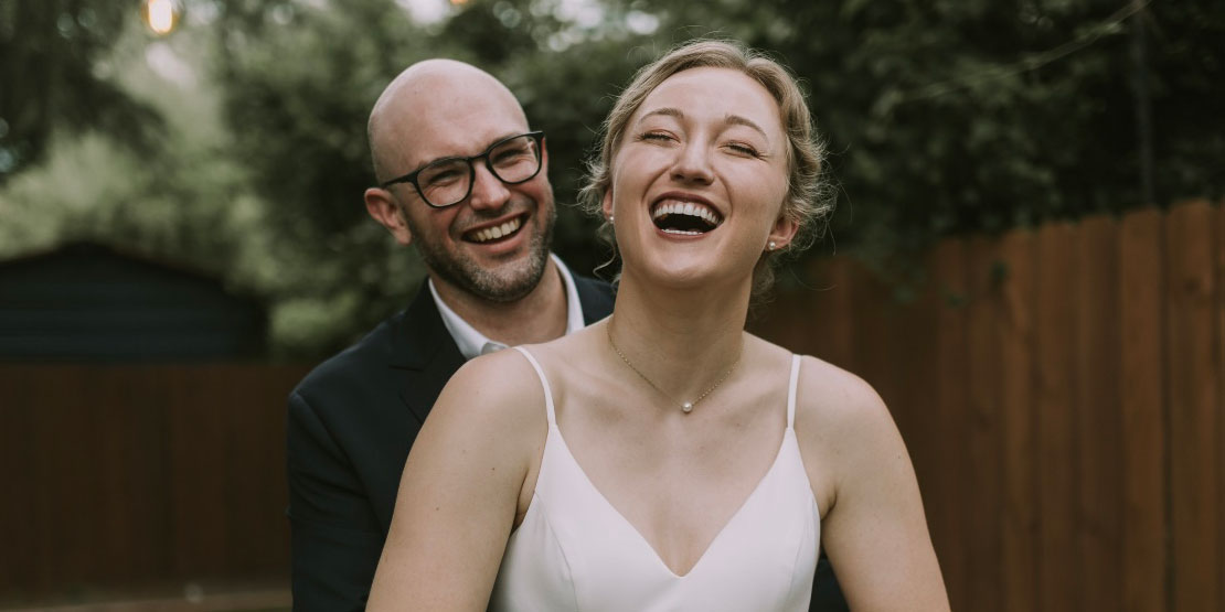 laughing bride and groom with trees in the background