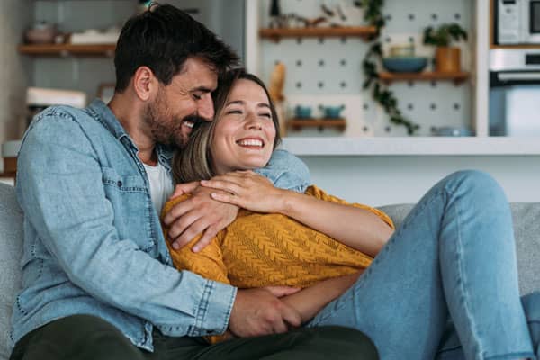 Shot of a cheerful young man hugging his girlfriend on the sofa at home.