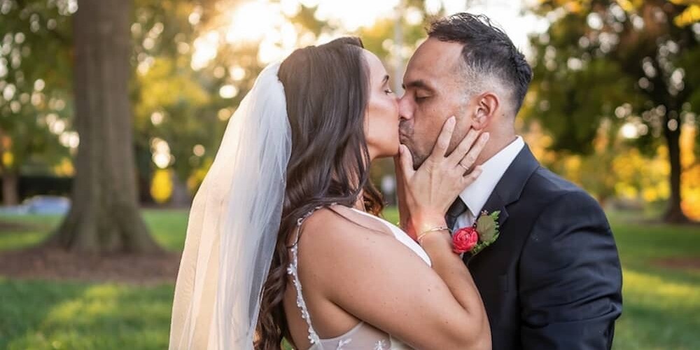 bride and groom kissing outside with trees